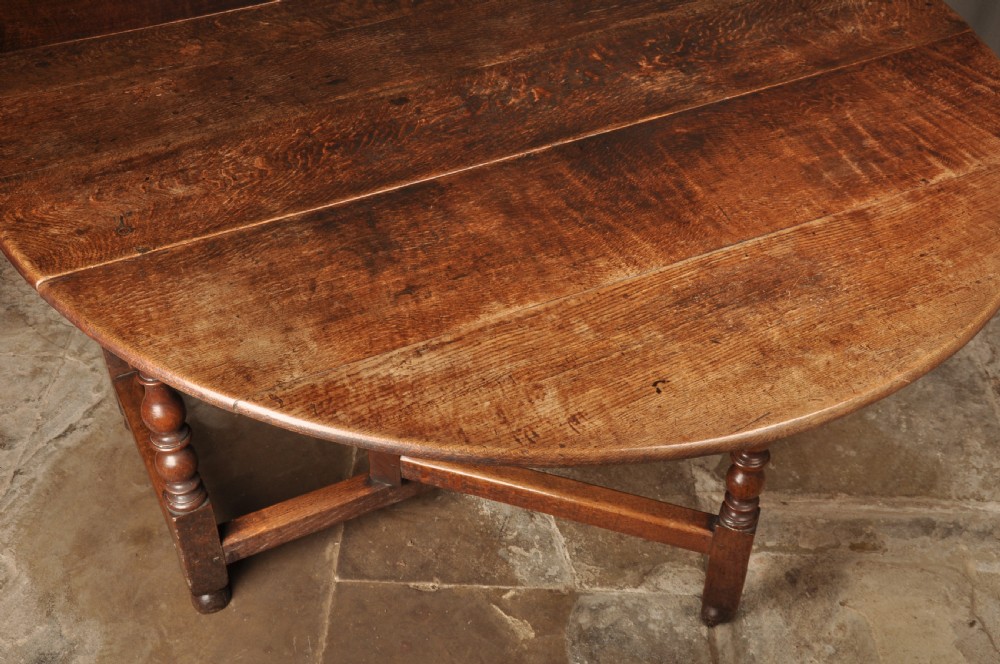 A large 17th-century solid oak gateleg dining table featuring drop leaves, turned legs, and perimeter stretchers. View IX