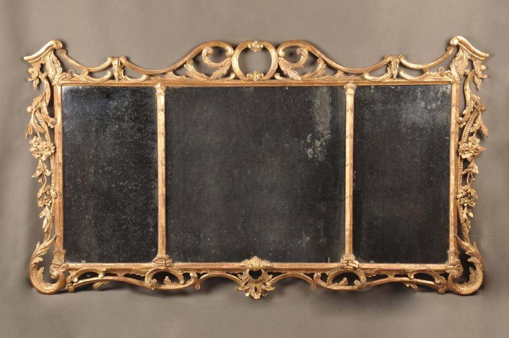 An 18th-century horizontal giltwood overmantel mirror featuring three glass plates set within a carved frame decorated with acanthus scrolls, C-scrolls, and floral motifs.