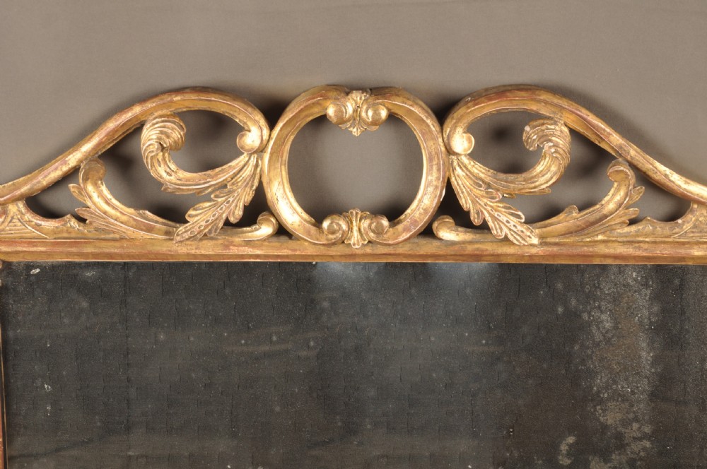 An 18th-century horizontal giltwood overmantel mirror featuring three glass plates set within a carved frame decorated with acanthus scrolls, C-scrolls, and floral motifs. View III