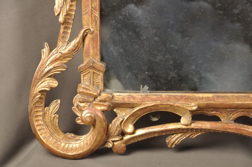 An 18th-century horizontal giltwood overmantel mirror featuring three glass plates set within a carved frame decorated with acanthus scrolls, C-scrolls, and floral motifs. View IV