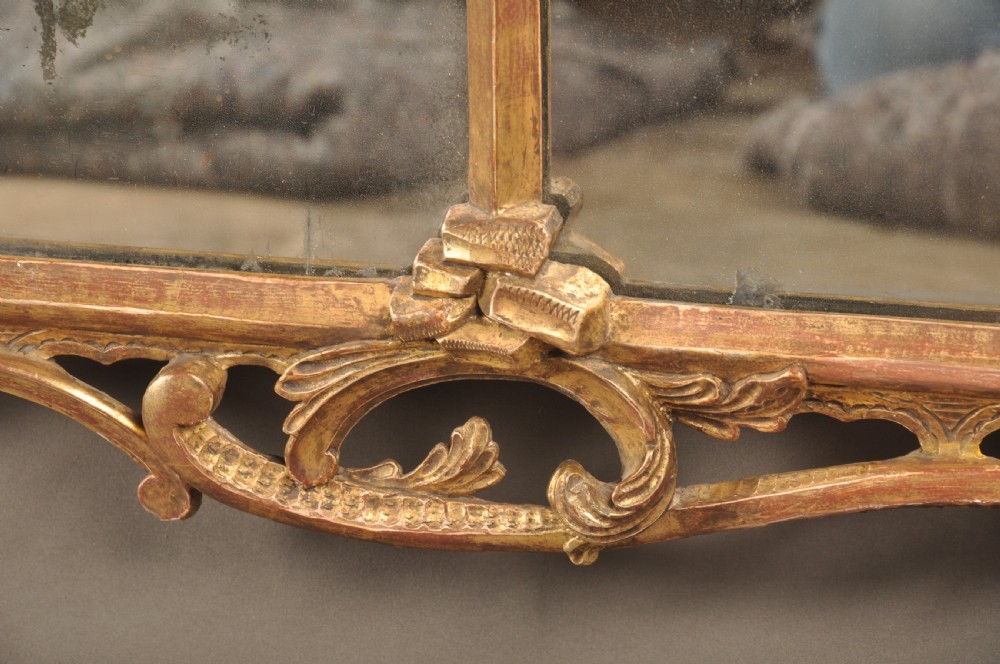 An 18th-century horizontal giltwood overmantel mirror featuring three glass plates set within a carved frame decorated with acanthus scrolls, C-scrolls, and floral motifs. View VIII