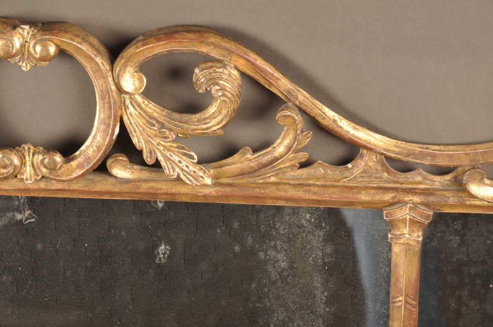 An 18th-century horizontal giltwood overmantel mirror featuring three glass plates set within a carved frame decorated with acanthus scrolls, C-scrolls, and floral motifs. View IX
