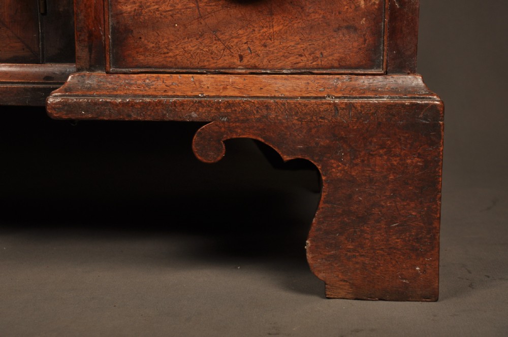 An 18th-century mahogany kneehole desk featuring a long upper drawer, six smaller side drawers, a central recessed cupboard, and bracket feet. View IV
