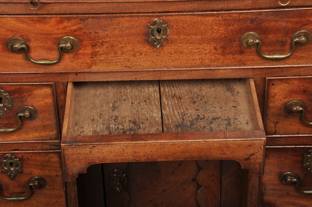 An 18th-century mahogany kneehole desk featuring a long upper drawer, six smaller side drawers, a central recessed cupboard, and bracket feet. View VII