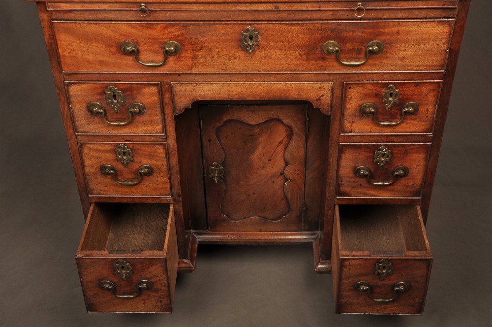 An 18th-century mahogany kneehole desk featuring a long upper drawer, six smaller side drawers, a central recessed cupboard, and bracket feet. View IX