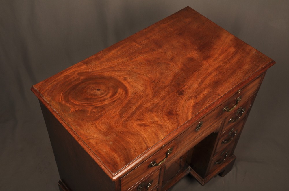 An 18th-century mahogany kneehole desk featuring a long upper drawer, six smaller side drawers, a central recessed cupboard, and bracket feet. View XI
