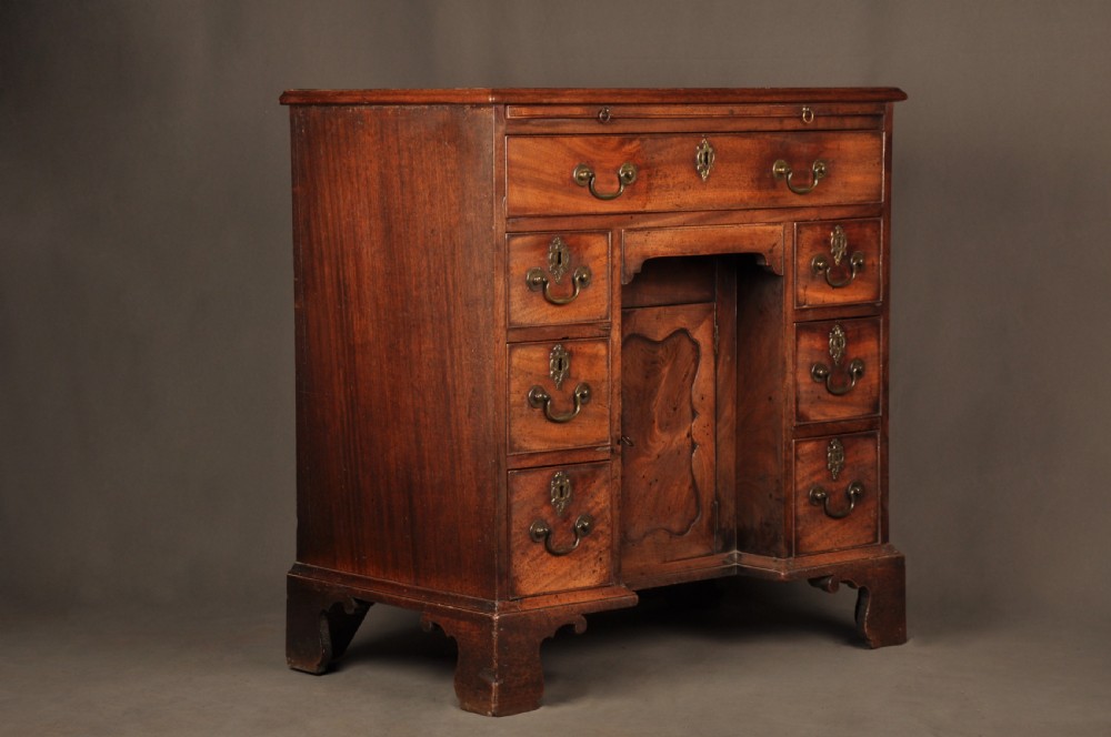An 18th-century mahogany kneehole desk featuring a long upper drawer, six smaller side drawers, a central recessed cupboard, and bracket feet. View XIV