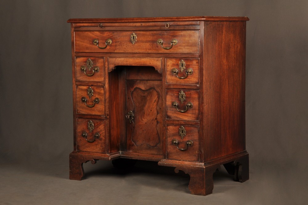 An 18th-century mahogany kneehole desk featuring a long upper drawer, six smaller side drawers, a central recessed cupboard, and bracket feet. View XV