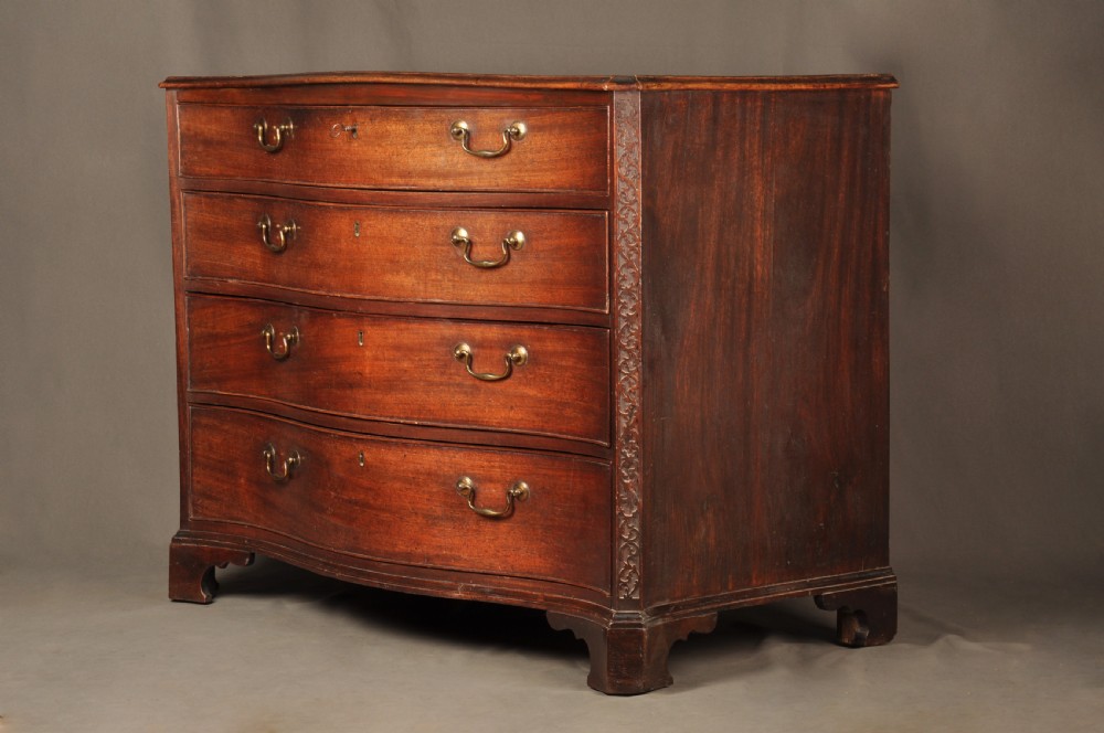 An 18th-century mahogany serpentine chest of drawers featuring four graduated drawers, carved canted corners, and brass swan-neck handles. View III