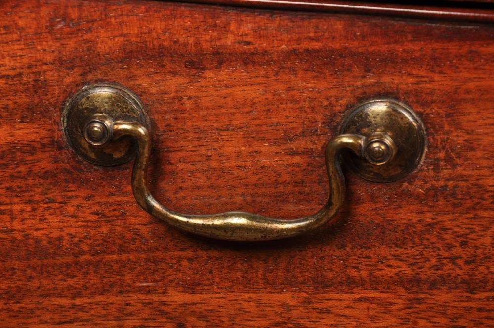 An 18th-century mahogany serpentine chest of drawers featuring four graduated drawers, carved canted corners, and brass swan-neck handles. View VI