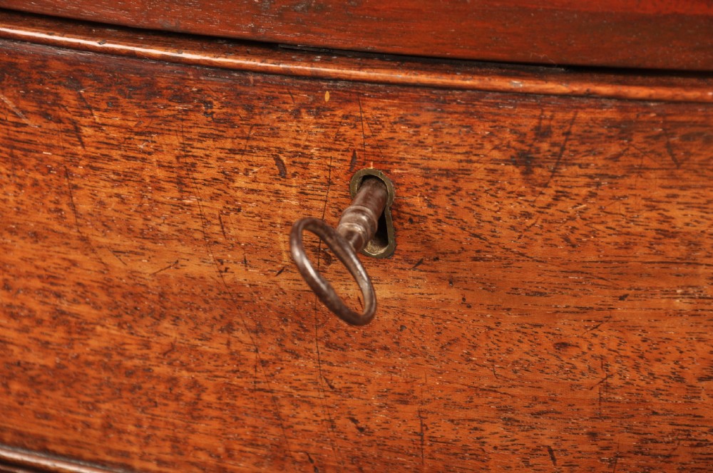 An 18th-century mahogany serpentine chest of drawers featuring four graduated drawers, carved canted corners, and brass swan-neck handles. View VII
