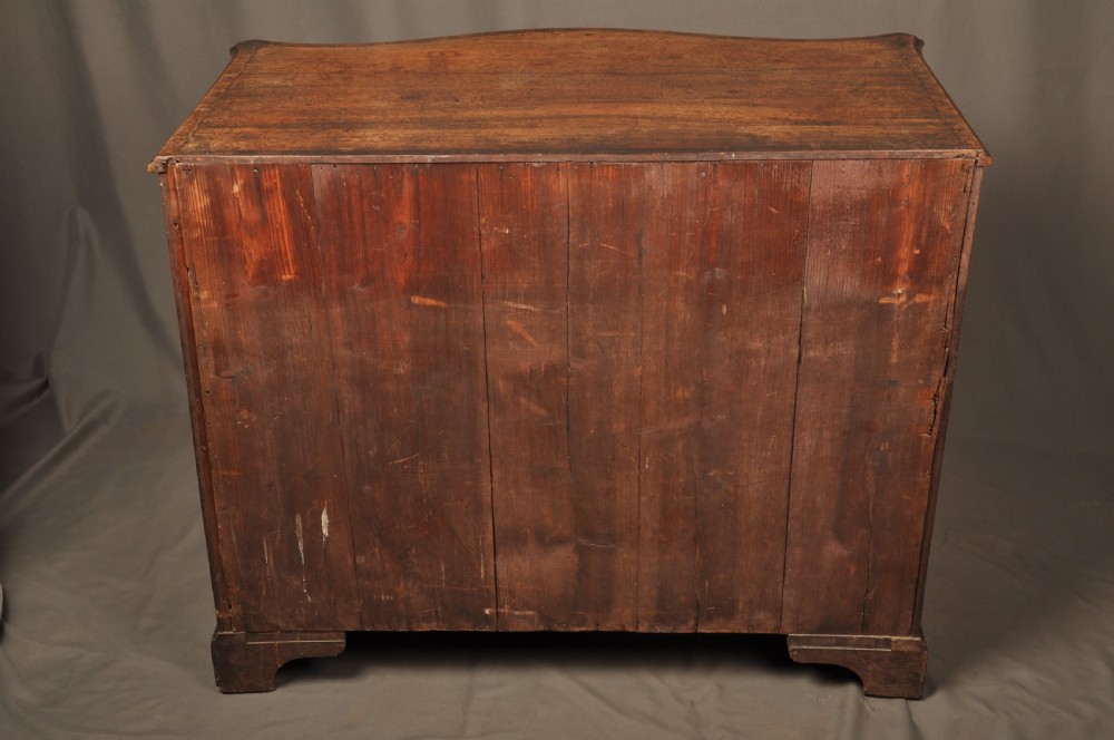 An 18th-century mahogany serpentine chest of drawers featuring four graduated drawers, carved canted corners, and brass swan-neck handles. View XIV