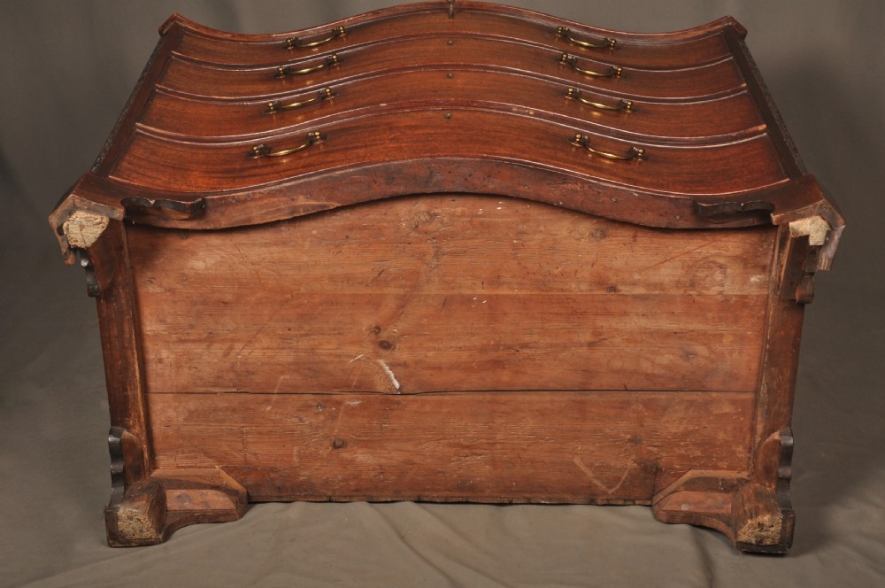 An 18th-century mahogany serpentine chest of drawers featuring four graduated drawers, carved canted corners, and brass swan-neck handles. View XV