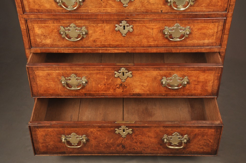 An early George II burr walnut chest of drawers featuring four graduated drawers with brass handles, a brushing slide, featherbanding, and bracket feet. View IX