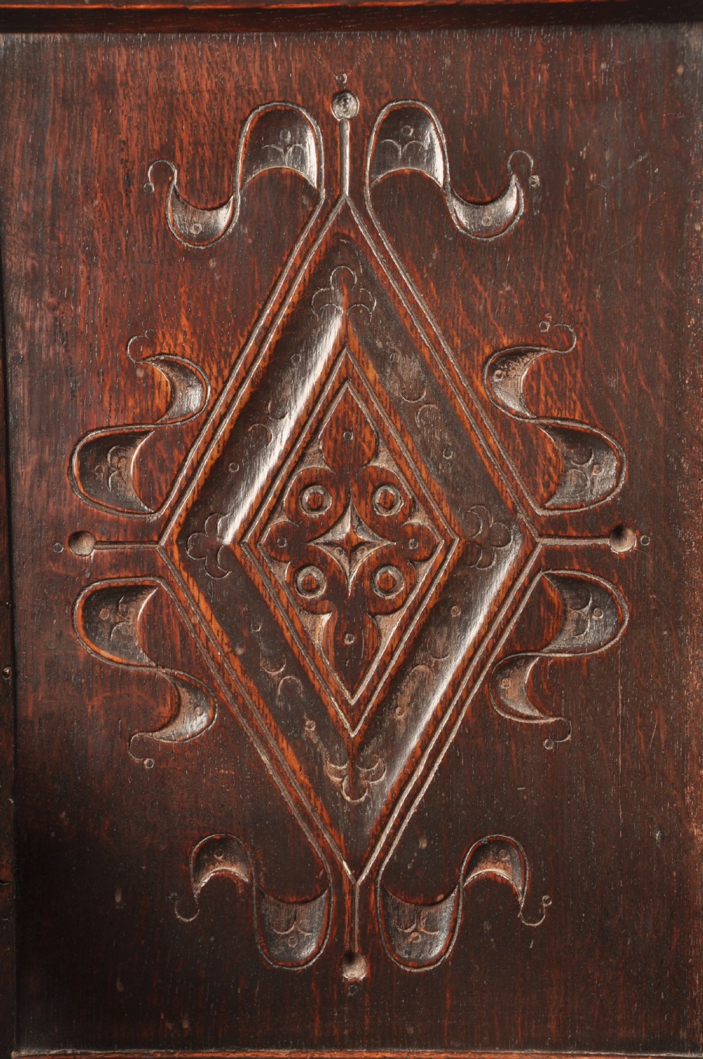 A 17th-century dark oak wainscot armchair featuring a carved scroll cresting, lozenge-carved back panel, shaped armrests, and turned front legs. View IV
