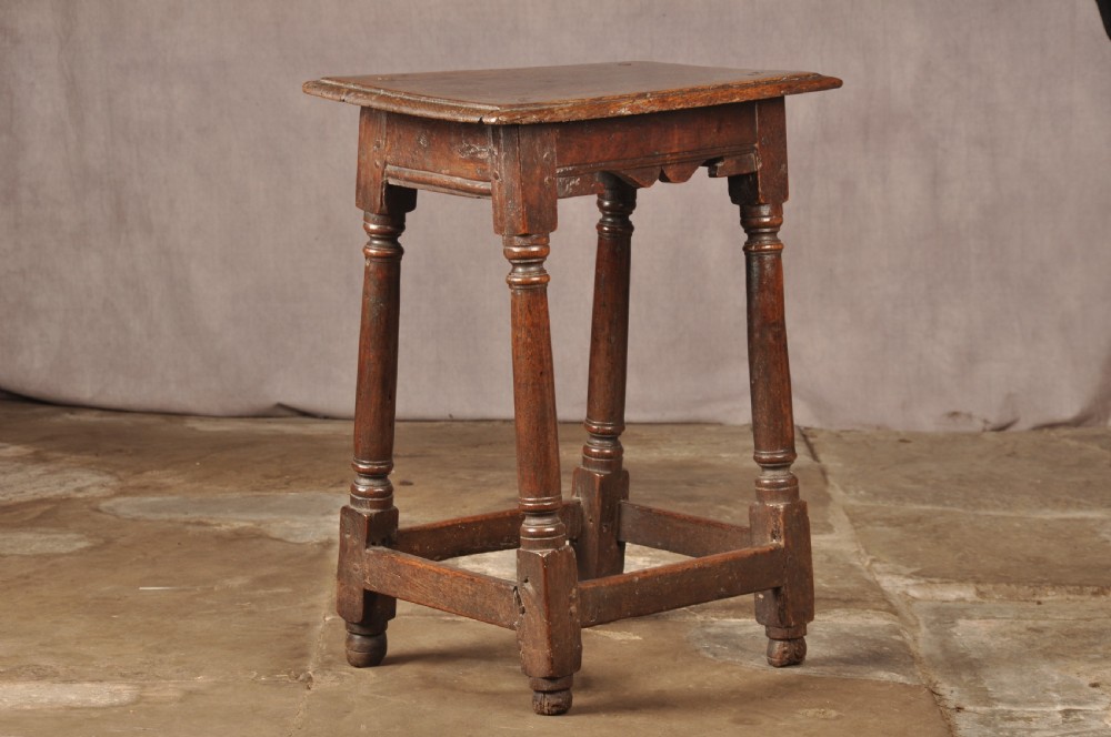 A mid-17th-century solid oak joint stool featuring turned legs, a rectangular top, and lower perimeter stretchers. View IV