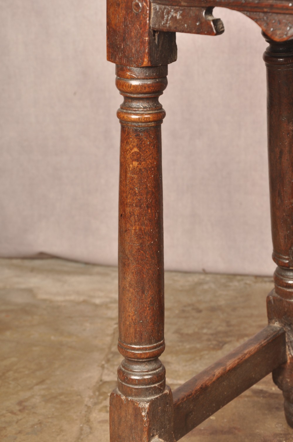 A mid-17th-century solid oak joint stool featuring turned legs, a rectangular top, and lower perimeter stretchers. View IX