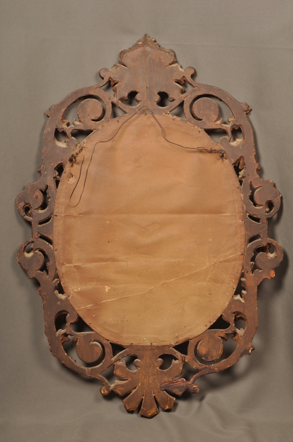 An antique oval giltwood wall mirror featuring an intricately carved openwork frame decorated with scrolling acanthus leaves, C-scrolls, rope moulding, and shell cresting. View VII
