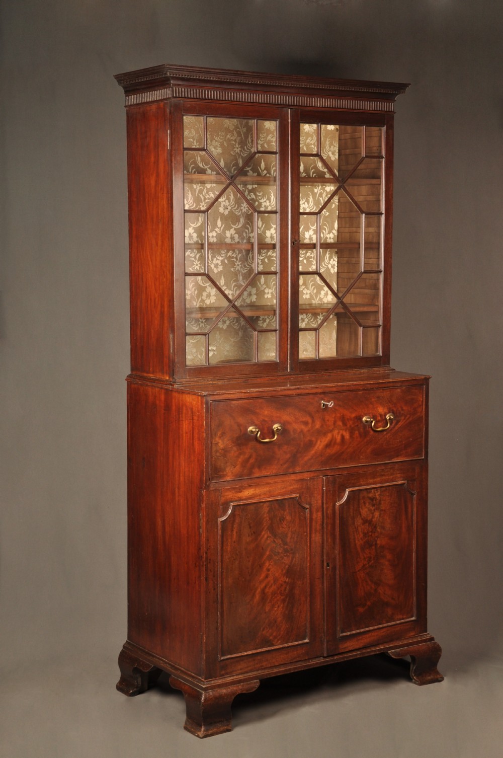 An 18th-century mahogany secretaire bookcase featuring a dentil cornice, astragal-glazed upper cabinet doors, a drop-front writing drawer with brass handles, and a two-door lower cupboard resting on bracket feet. View II