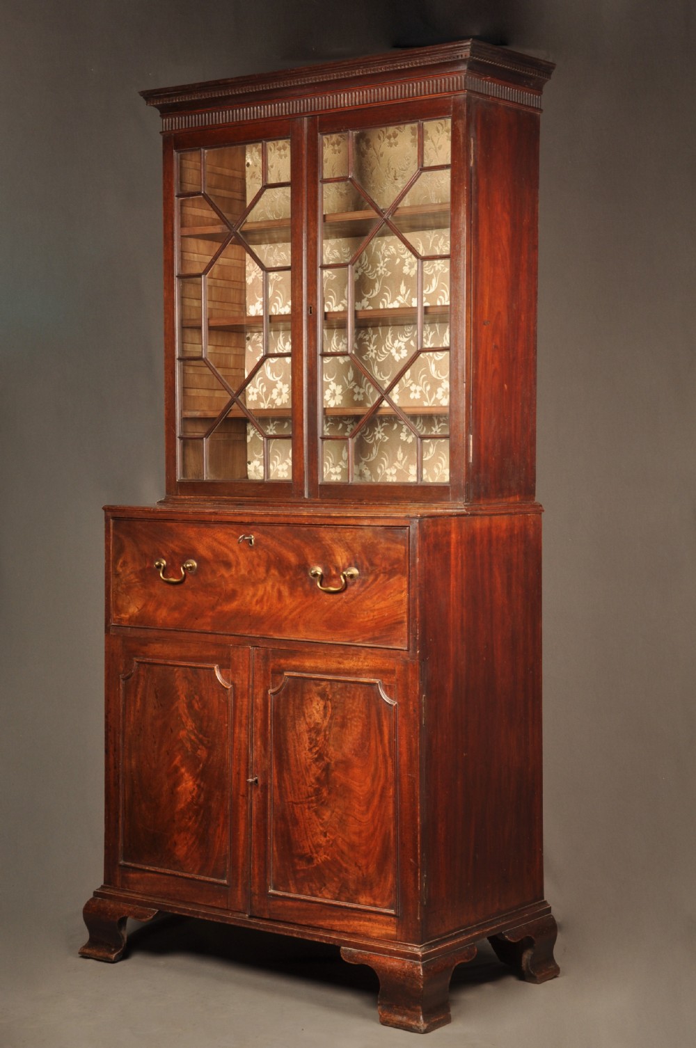 An 18th-century mahogany secretaire bookcase featuring a dentil cornice, astragal-glazed upper cabinet doors, a drop-front writing drawer with brass handles, and a two-door lower cupboard resting on bracket feet. View III