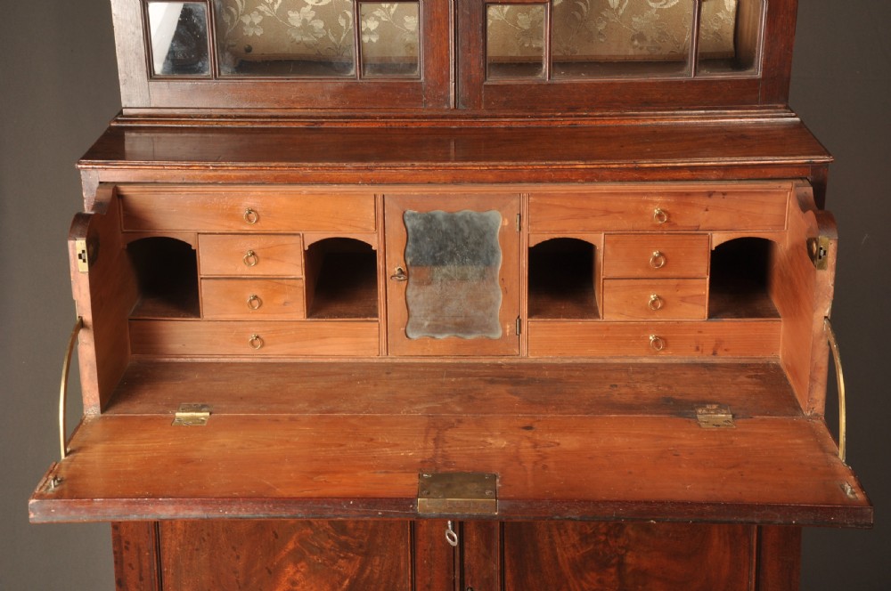 An 18th-century mahogany secretaire bookcase featuring a dentil cornice, astragal-glazed upper cabinet doors, a drop-front writing drawer with brass handles, and a two-door lower cupboard resting on bracket feet. View V