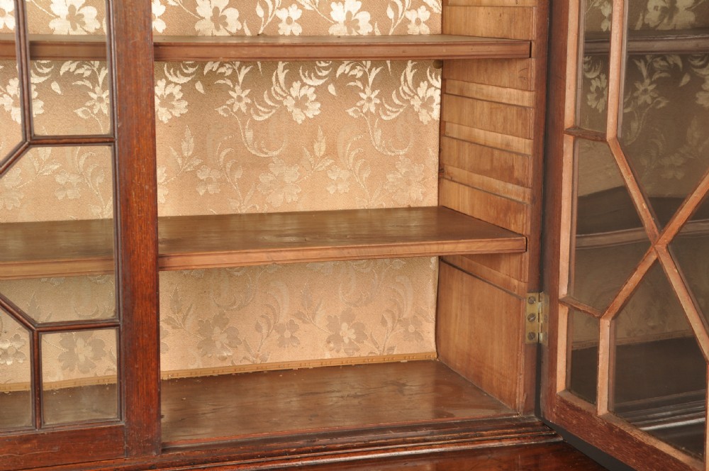 An 18th-century mahogany secretaire bookcase featuring a dentil cornice, astragal-glazed upper cabinet doors, a drop-front writing drawer with brass handles, and a two-door lower cupboard resting on bracket feet. View XIV