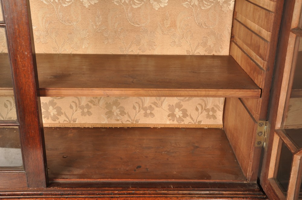 An 18th-century mahogany secretaire bookcase featuring a dentil cornice, astragal-glazed upper cabinet doors, a drop-front writing drawer with brass handles, and a two-door lower cupboard resting on bracket feet. View XV