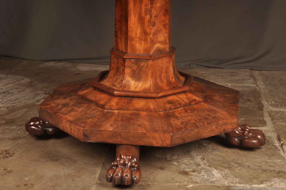 A circular Regency mahogany breakfast table featuring flame mahogany radial veneers, a faceted pedestal, and carved lion paw feet. View III