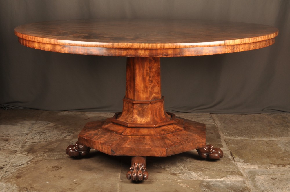 A circular Regency mahogany breakfast table featuring flame mahogany radial veneers, a faceted pedestal, and carved lion paw feet. View IV