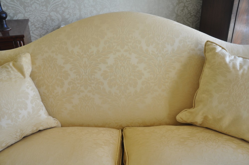 A 19th-century camelback settee upholstered in patterned yellow damask fabric with brass studding and carved mahogany legs featuring lion mask motifs. View VII