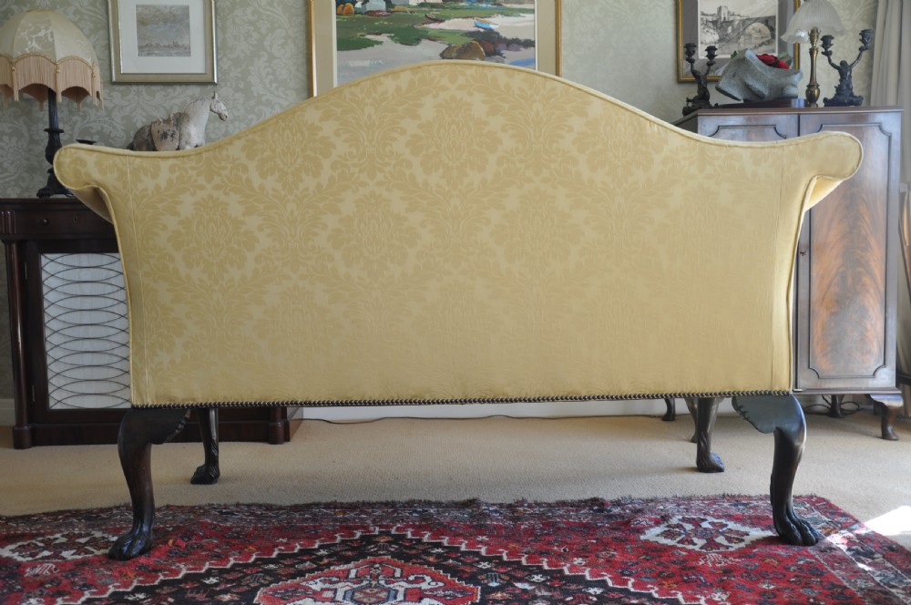 A 19th-century camelback settee upholstered in patterned yellow damask fabric with brass studding and carved mahogany legs featuring lion mask motifs. View IX