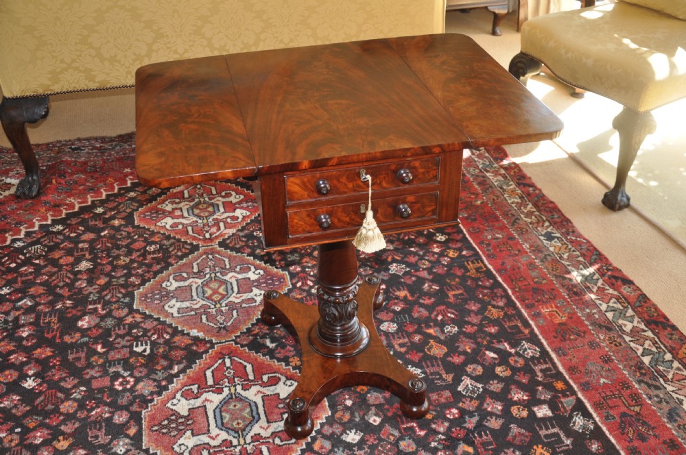 A Regency flame mahogany Pembroke table featuring two drop leaves, two small drawers with turned wooden handles, a carved turned pedestal support, and a quadruped platform base. View VIII