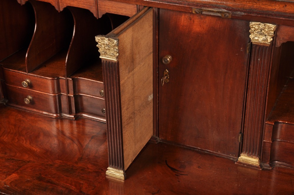 An 18th-century mahogany bureau cabinet featuring an architectural pediment top, two panelled upper doors, a slant-front writing desk, and lower drawers on bracket feet. View V