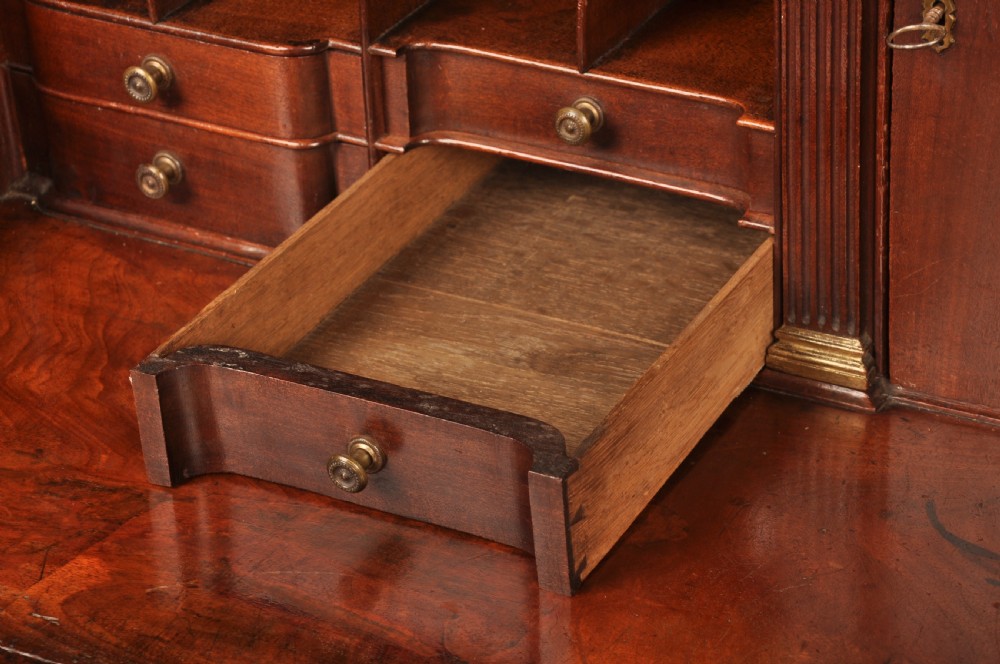 An 18th-century mahogany bureau cabinet featuring an architectural pediment top, two panelled upper doors, a slant-front writing desk, and lower drawers on bracket feet. View VIII