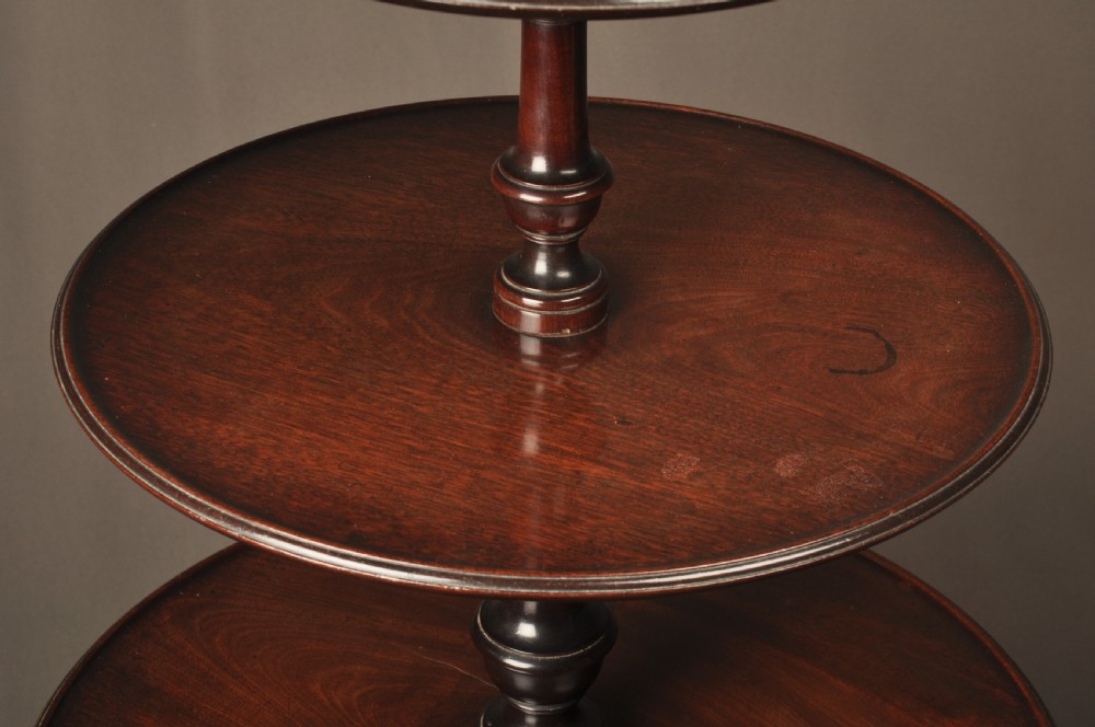 An 18th-century mahogany three-tiered dumb waiter featuring graduated dished trays, a turned central column, and tripod cabriole legs. View V