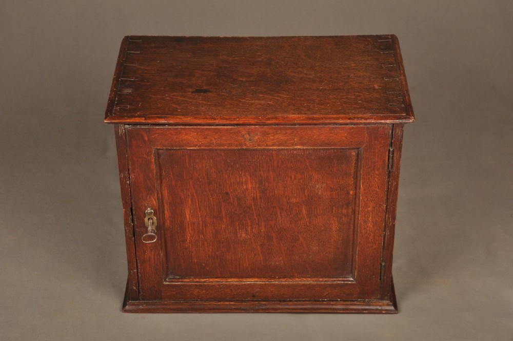 A mid-18th-century oak spice cupboard featuring a single fielded panel door with a brass keyhole escutcheon and a moulded base. View III