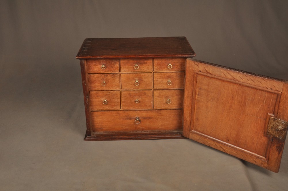 A mid-18th-century oak spice cupboard featuring a single fielded panel door with a brass keyhole escutcheon and a moulded base. View V