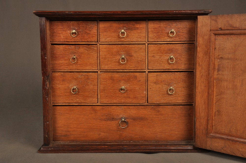 A mid-18th-century oak spice cupboard featuring a single fielded panel door with a brass keyhole escutcheon and a moulded base. View VI
