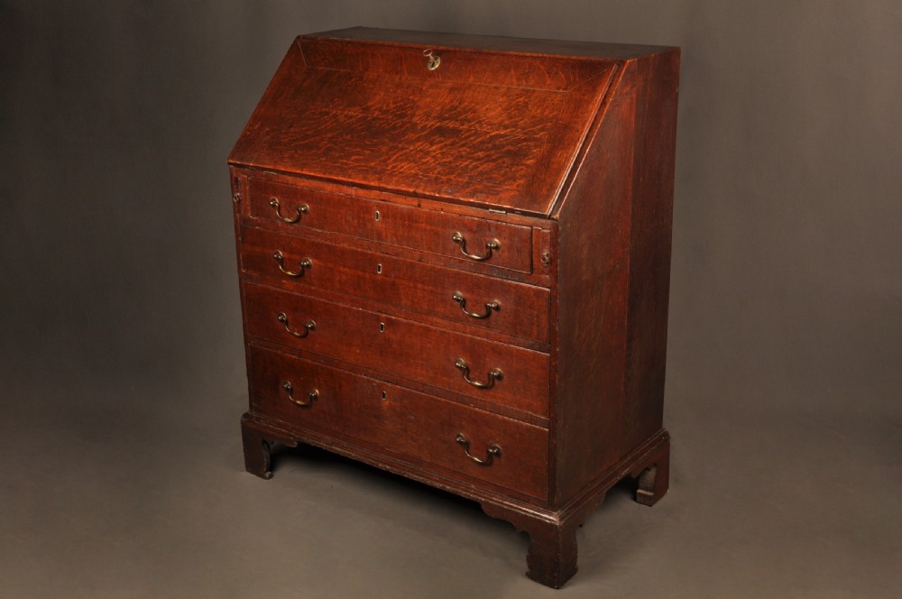 A mid-18th-century warm brown oak slant-front writing bureau featuring four graduated drawers with brass swan-neck handles and bracket feet. View III