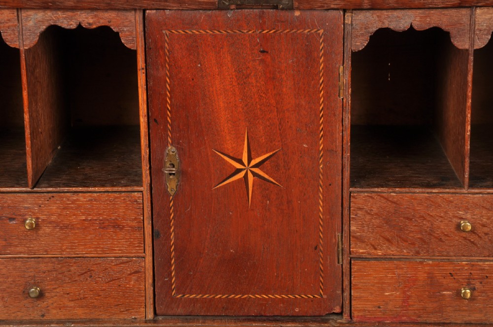 A mid-18th-century warm brown oak slant-front writing bureau featuring four graduated drawers with brass swan-neck handles and bracket feet. View XIII