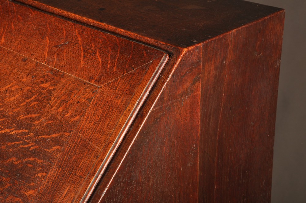 A mid-18th-century warm brown oak slant-front writing bureau featuring four graduated drawers with brass swan-neck handles and bracket feet. View XVIII