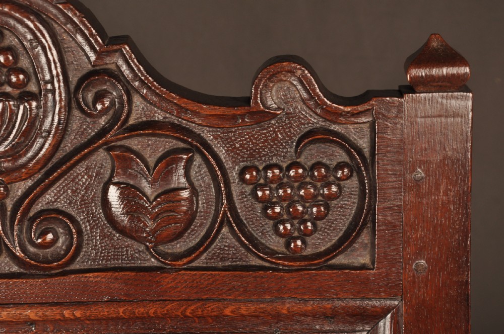 A seventeenth-century dark oak wainscot armchair featuring a carved back panel with floral motifs, turned supports, and shaped armrests. View XI