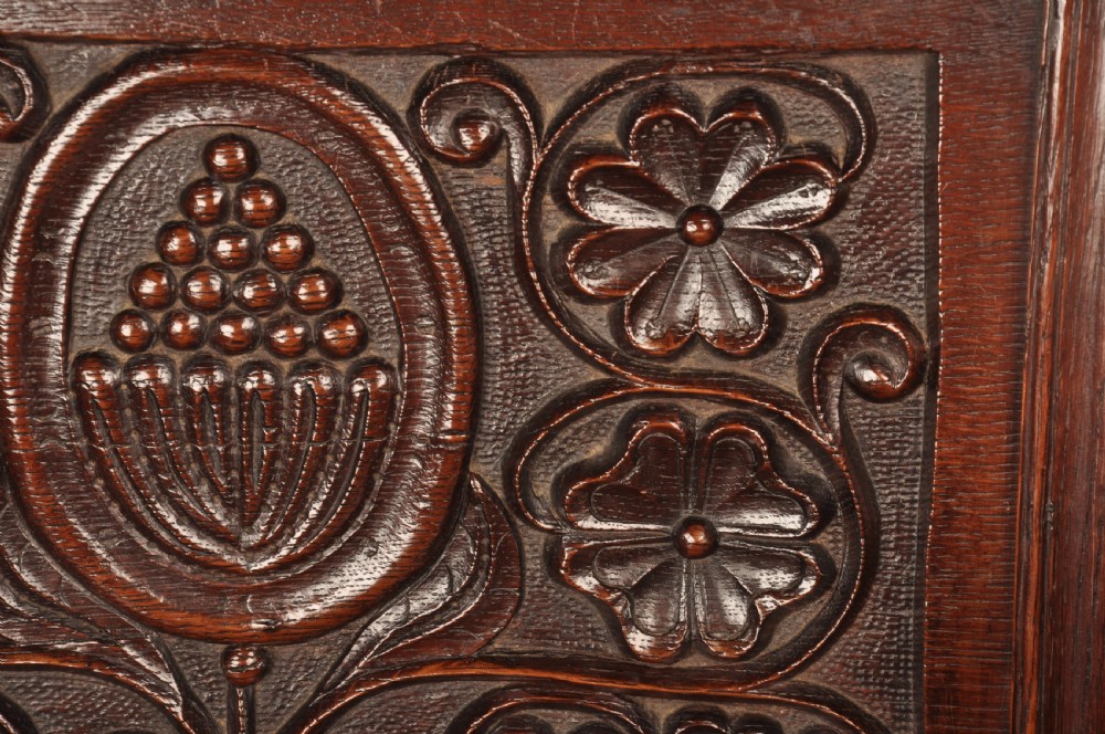 A seventeenth-century dark oak wainscot armchair featuring a carved back panel with floral motifs, turned supports, and shaped armrests. View XIII