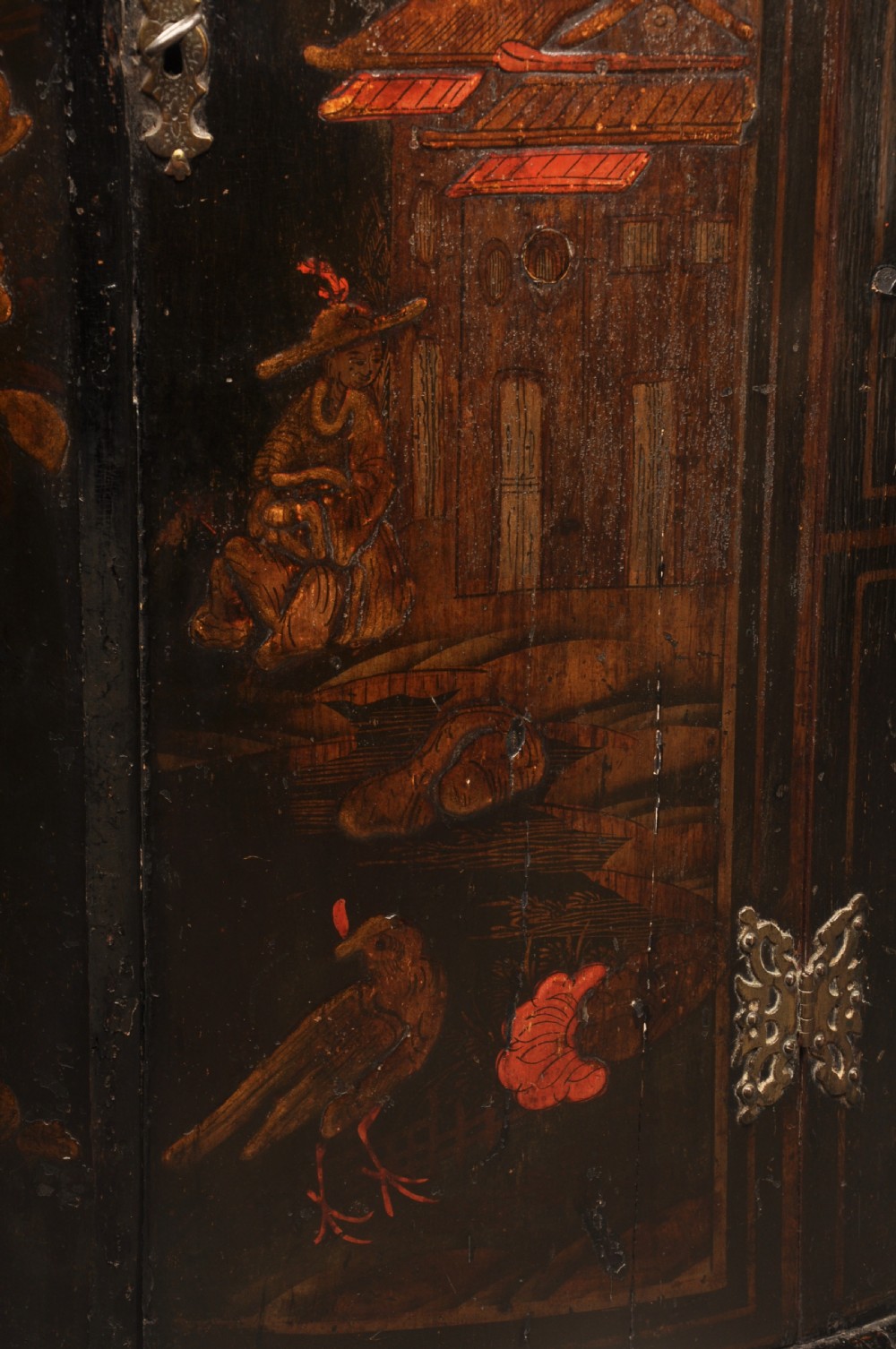 An early 18th-century black japanned hanging corner cupboard featuring hand-painted chinoiserie decoration depicting birds, flora, and architectural structures with brass butterfly hinges. View V