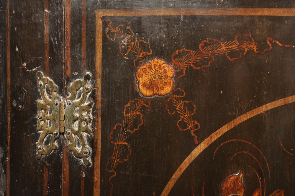 An early 18th-century black japanned hanging corner cupboard featuring hand-painted chinoiserie decoration depicting birds, flora, and architectural structures with brass butterfly hinges. View VI