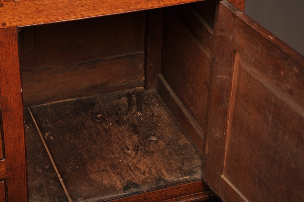 An eighteenth-century warm brown oak dresser featuring an upper three-tier open plate rack above a lower cabinet with drawers and panelled cupboard doors. View IX