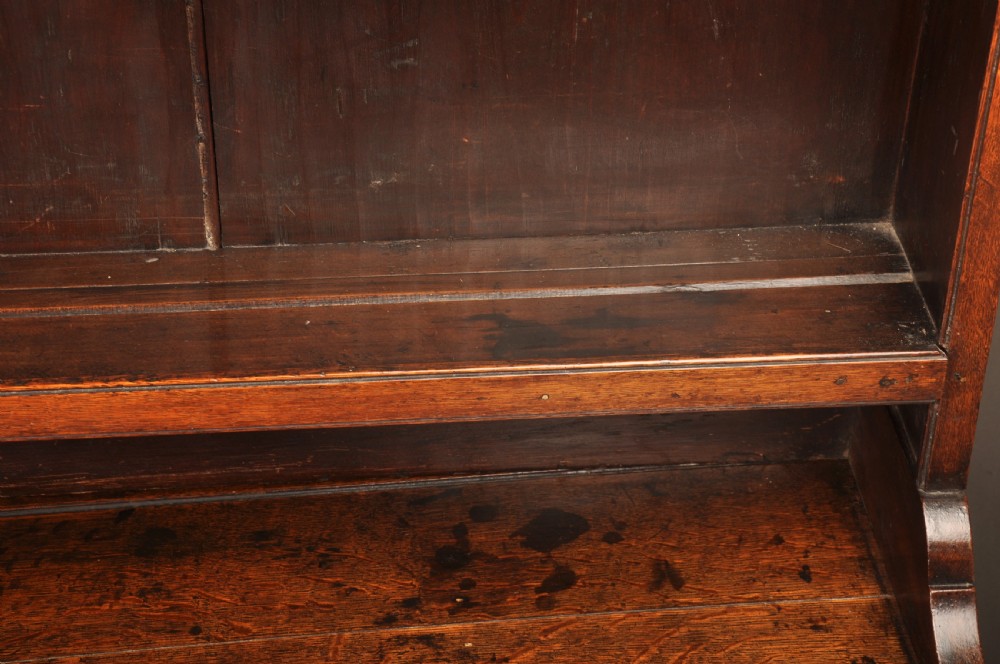 An eighteenth-century warm brown oak dresser featuring an upper three-tier open plate rack above a lower cabinet with drawers and panelled cupboard doors. View XIII