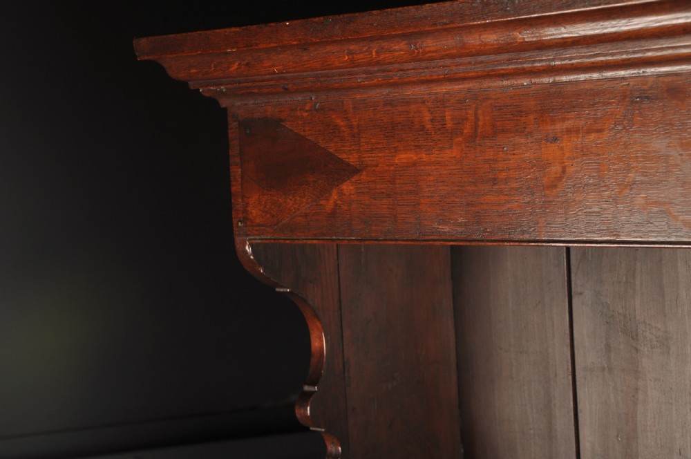 An eighteenth-century warm brown oak dresser featuring an upper three-tier open plate rack above a lower cabinet with drawers and panelled cupboard doors. View XV