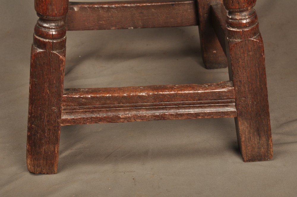 An 18th-century oak joint stool featuring baluster turned legs, plain stretchers, a rectangular moulded top, and dark brown patinated wood. View IX