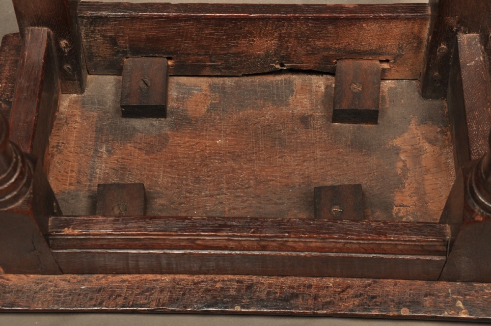 An 18th-century oak joint stool featuring baluster turned legs, plain stretchers, a rectangular moulded top, and dark brown patinated wood. View XII